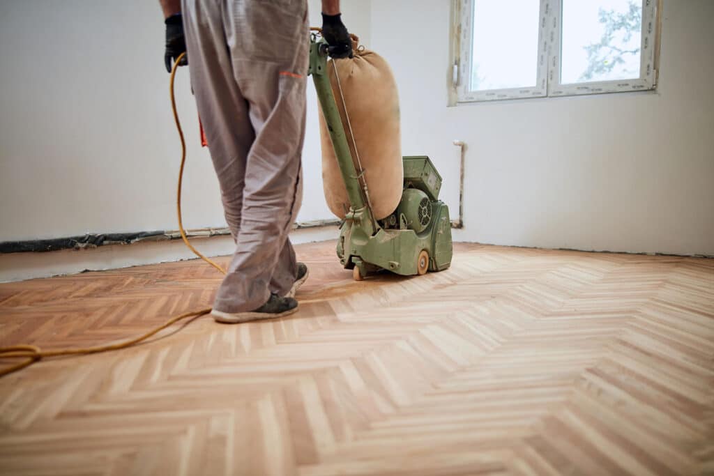 Fagmann i arbeid med gulvsliping av tregulv i bolig